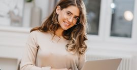Photo Of Lovely White Woman In Glasses Using Computer With Charming Smile Indoor Portrait Of Stunning Student With Curly Hair Studying With Laptop