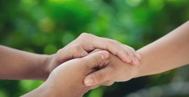 Couple Holding Hands In Green Meadow