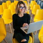 Portrait Of Young Attractive Woman Sitting In Lecture Hall Working On Laptop Portrait Of Young Attractive Woman Sitting In Lecture Hall Working On Laptop